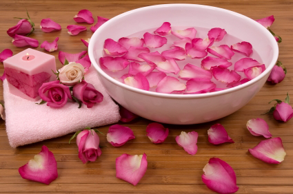 Pink flower petals scattered in and around a white ceramic bowl.